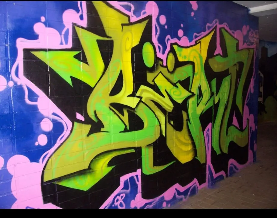Grünes Graffiti-Lettering auf blau-pinker Wand