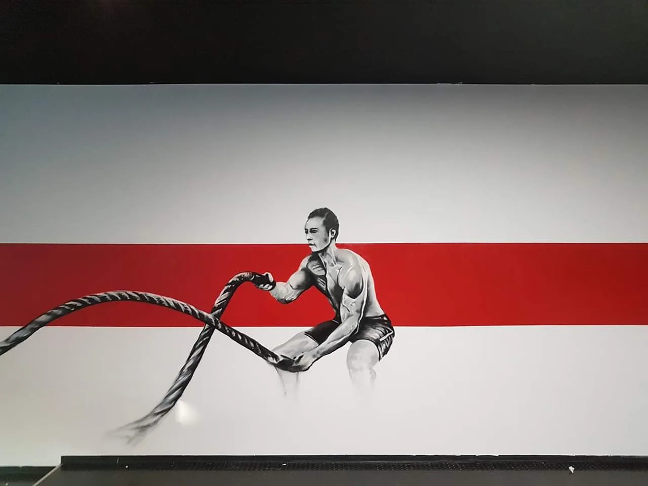 Schwarz-rotes Wandbild einer Sportlerin mit Trainingsseilen