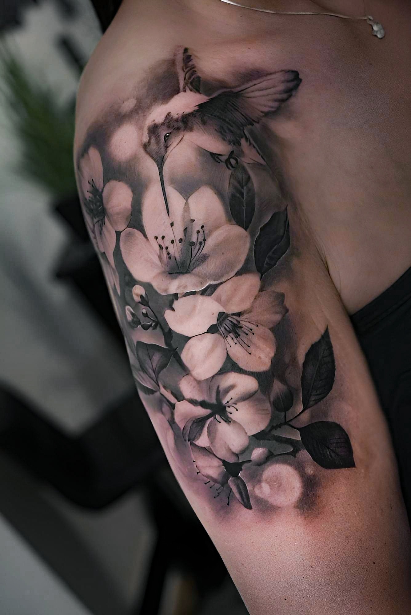 Black-and-Grey-Tattoo mit Kolibri und großflächigen Blüten